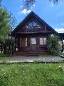 a wooden house with a porch and a grass yard at Cabañas Entre Rios in Concepción del Uruguay