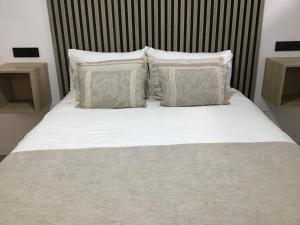 Una cama con sábanas blancas y almohadas en un dormitorio. en Casa Garnier, en Santa Cruz de la Palma