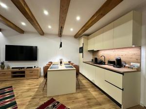 a kitchen with white cabinets and a flat screen tv at Central House - Modern Apartment in Zărneşti +11 photos