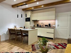 a kitchen with white cabinets and a table with chairs at Central House - Modern Apartment in Zărneşti
