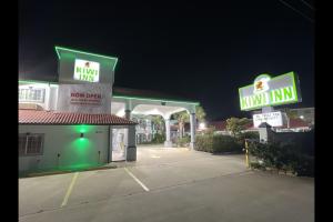 ヒューストンにあるKiwi Inn Capital O Houston - Hwy 249のネオンサインが2つある夜のガソリンスタンド