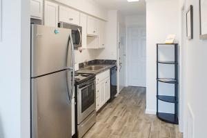 a kitchen with a stainless steel refrigerator and wooden floors at Assateague House 511 in Ocean City