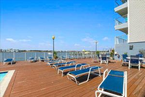 a deck with a bunch of lounge chairs and a pool at Assateague House 511 in Ocean City +10 photos