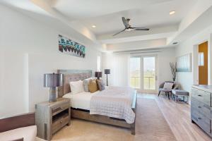 a white bedroom with a bed and a dresser at Padre Villa 104 in Padre Island
