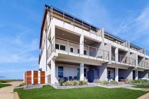 an apartment building with a balcony and grass at Padre Villa 104 in Padre Island