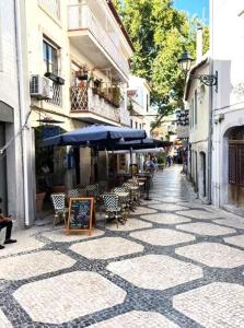 una calle vacía con mesas, sillas y una sombrilla en Cascais By the Ocean, en Cascais