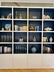 een witte boekenplank vol met glazen en boeken bij Charmante petite maison d'exception classée in Saint-Brieuc