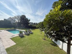 un cortile con piscina e alcuni alberi di THE SURF AND GOLF HUIS Solar Power a St Francis Bay