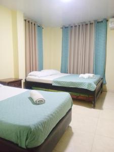 two beds in a room with blue curtains at Apartamento central Yahweh in San Andrés +17 photos