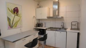 a small kitchen with white cabinets and a sink at Fresh And Cozy Little House 30km In Täby in Stockholm