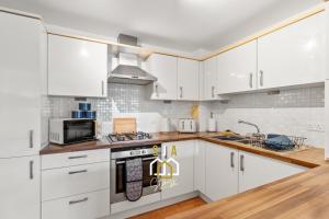 a kitchen with white cabinets and a stove top oven at Hammerman Residence - SJA Stays - 3 Bed Apartment With Parking in Aberdeen