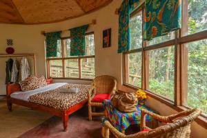 a bedroom with a bed and chairs and windows at Gorilla Retreat Ecolodge -Bwindi Forest in Bwindi +82 photos