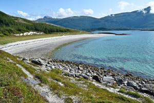 a beach with rocks and water with mountains in the background at Leilighet i i vakre Skivika, Bodø Gratis parkering og rolige omgivelser nært sentrum in Bodø