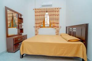 a bedroom with a bed and a dresser and two windows at Joy Villa Garden in Batticaloa