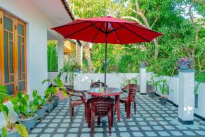 a table and chairs with a red umbrella on a patio at Joy Villa Garden in Batticaloa