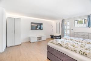 a white bedroom with a bed and a tv at Completely renovated, furnished studio with plenty of comfort in Visp