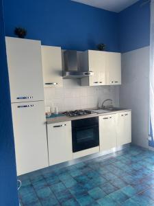 a kitchen with white cabinets and a stove top oven at Tower casa vacanze 2 in Anzio +6 photos