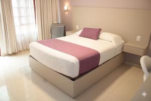a bedroom with a large bed with a purple pillow at Hotel Santa Rosa in Oaxaca City +13 photos