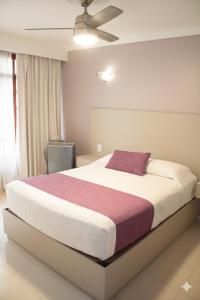 a bedroom with a large bed with a purple pillow at Hotel Santa Rosa in Oaxaca City
