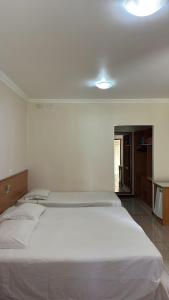 a bedroom with a large white bed in a room at Hotel Lago Alphaville in Apucarana