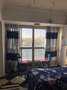 a bedroom with a bed and two chairs and a window at Aisha guesthouse in Aswan
