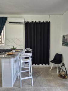 a kitchen with black curtains and white stools at OMY Apartments Nagua 1B in Nagua