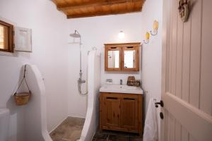a bathroom with a sink and a wooden door at Lithea Villas and Studios by the Sea in Aghios Petros Alonissos