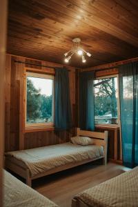 a bedroom with two beds and two windows at Pauliankos slėnis 1 in Krakiai
