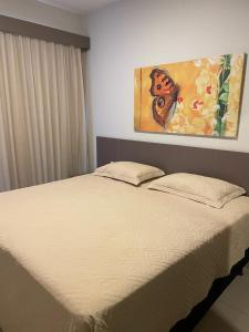 Una cama en un dormitorio con un cuadro en la pared. en Park Veredas Apto 705, en Rio Quente