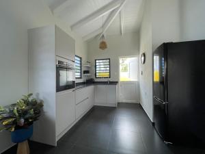 a kitchen with white cabinets and a black refrigerator at CasaPuru-at-JanThiel in Jan Thiel