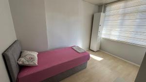 a small bedroom with a purple bed in a room with a window at Hostelida Konya in Konya