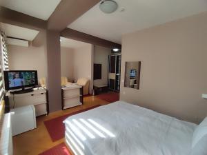 Schlafzimmer mit einem weißen Bett und einem Flachbild-TV in der Unterkunft Premier Hotel in Skopje