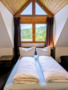 a bed with two pillows in front of a window at Eulennest im Ferienhaus an der Holzecke in Schnelldorf