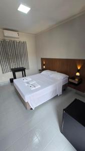 a bedroom with a large white bed and a television at Hotel Barretos Express in Barretos