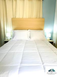 uma grande cama branca com uma cabeceira de madeira em Elegant apartment in San Pedro Sula em San Pedro Sula mais 3 fotografias