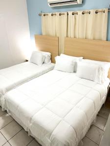 duas camas em um quarto com lençóis brancos em Elegant apartment in San Pedro Sula em San Pedro Sula