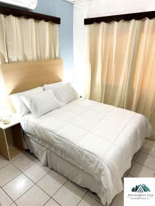 a bed with white sheets and pillows next to a window at Elegant apartment in San Pedro Sula in San Pedro Sula