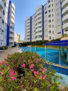 a swimming pool with pink flowers in front of buildings at Águas da Serra Apto 520A in Rio Quente