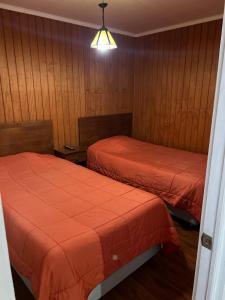 two beds in a room with wood paneling at Hotel Plaza Los Leones in Curanilahue