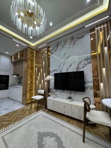 a living room with a television and a chandelier at Nest One Luxe, Элитные апартаменты с террасой и панорамным видом 067 in Tashkent