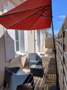 a red umbrella on a balcony with chairs and tables at Petite maison cœur de ville de La Teste de Buch in La Teste-de-Buch