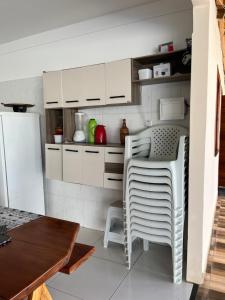 a kitchen with white cabinets and a table and chairs at Casa ponta da tulha in Ilhéus
