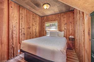 Un dormitorio con una cama en una pared de madera. en The Big Bear Lakefront Lodge, en Big Bear Lake