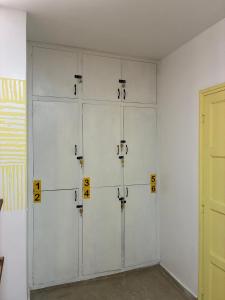 Una habitación con cuatro armarios blancos con números en ellos. en Colibrí - Smart Hostel, en San Juan