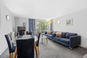 a living room with a blue couch and a table at Ensuite Room in Canary Wharf with attached Bathroom in London