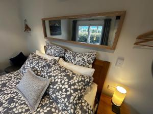 a bedroom with a bed with pillows and a mirror at Two Rivers Ohakune - Boutique Bed and Breakfast in Ohakune
