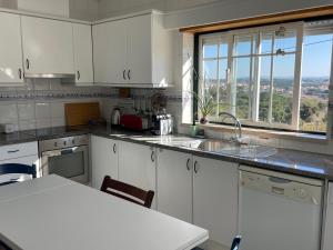 a kitchen with white cabinets and a large window at Casa da Foz do arelho in Nadadouro