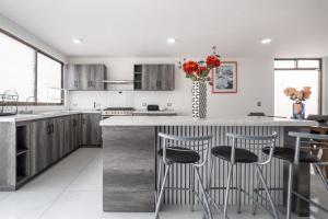 a kitchen with a counter with chairs and a vase with flowers at Casa Adul Chignahuapan in Chignahuapan