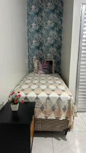 Un dormitorio con una cama y una mesa con flores. en Aconchego Hospedagem, en Barreirinhas