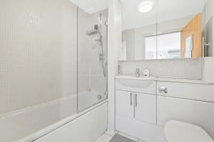 a white bathroom with a shower and a sink at Ensuite Room in Canary Wharf with attached Bathroom in London +9 photos